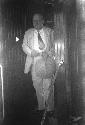 Man holding fan, standing on step in wood-panelled interior