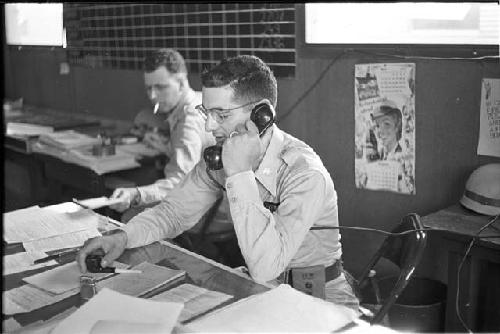 Man sitting at desk on telephone holding a pipe side view