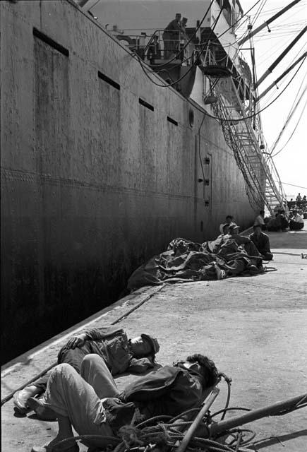 Men sleeping on waterfront waiting to aboard ship