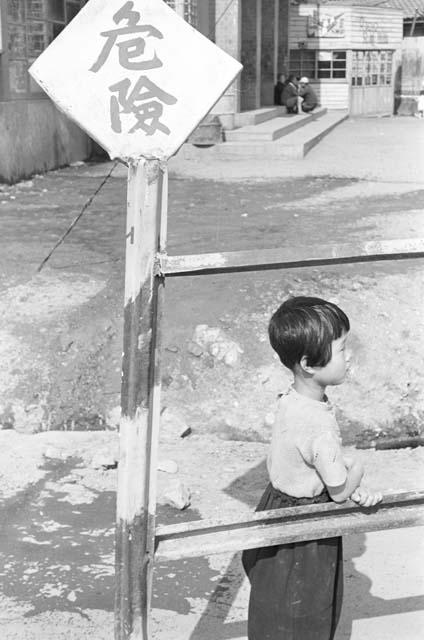 Kid outside leaning onto fence