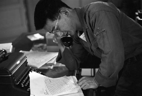 Man reading paper while talking on phone