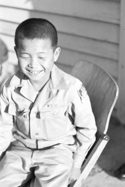 Portrait of boy in uniform sitting in chair