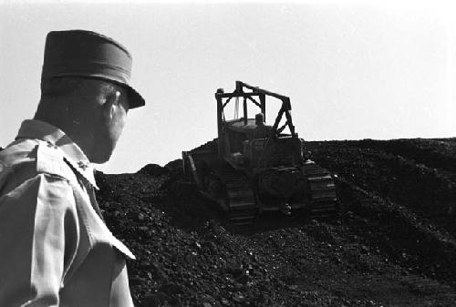 Portrait of tractor making way up dirt pile