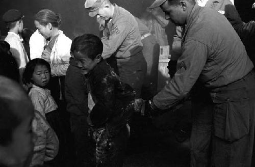 Portrait of boy in line being tagged by soldier