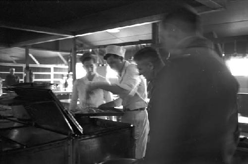 Chef pulling out food to show soldiers