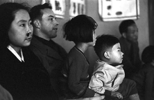 Family sitting down together looking ahead listening