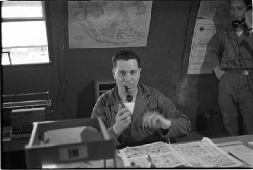 Soldier smoking pipe, soldier in background on telephone