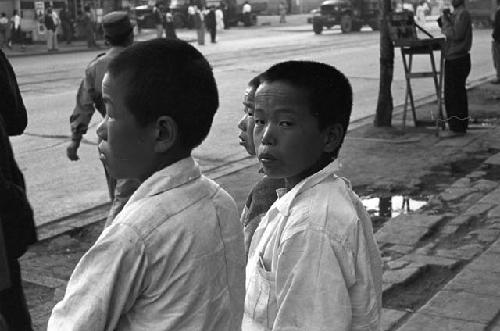 Boys standing on sidewalk staring at traffic