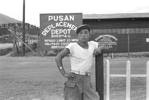 Man posing leaning against fence