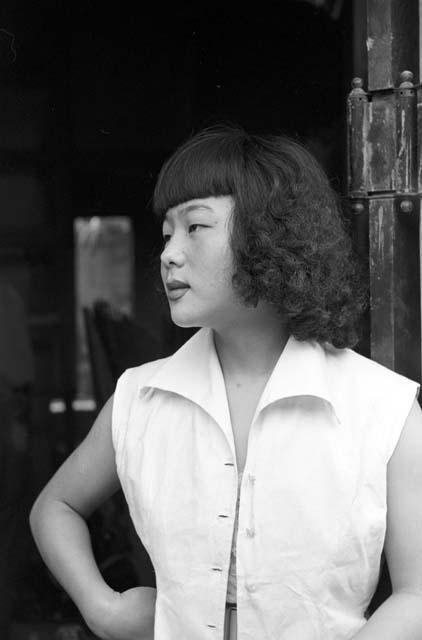 Portrait of woman standing by door wearing white shirt