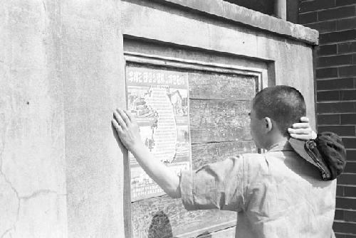 Portrait of man outside reading posted flyer