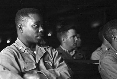 Portrait of soldier in audience sitting down with arms folded listening