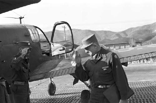 Soldier salutes general next to plane on base