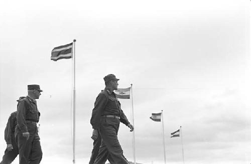 Portrait of soldiers walking outside with flagpoles in background