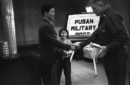 General shaking hands with man accompanying girls