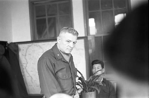 General looking in direction of men during meeting