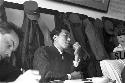 Man in suit sitting at table looking ahead