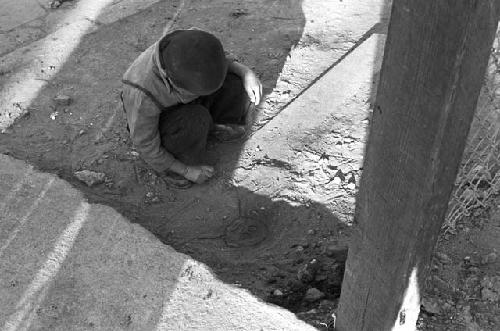 Boy on sidewalk playing with dirt