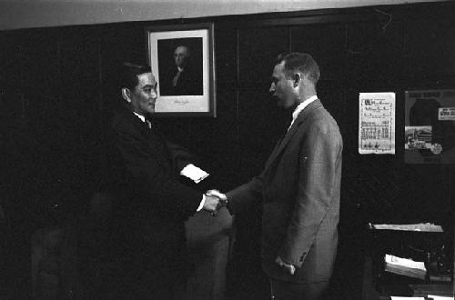 Men in suits meeting with each other going over letter 4