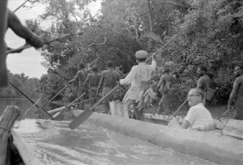 Gerbrands seated in a canoe while other men paddle down river