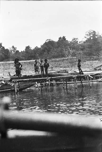 Men standing on dock with boats and canoes