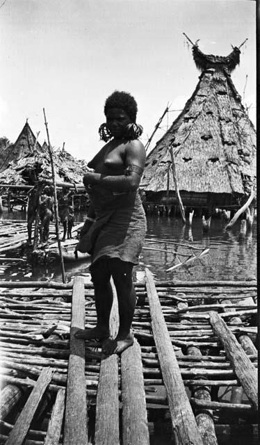 Woman with large earrings by triangular hut with crescent moon shaped top