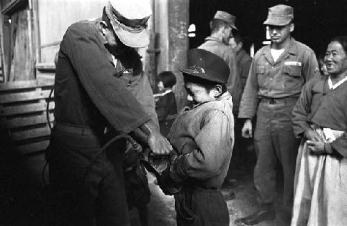 U.S. soldier spraying child with insecticide