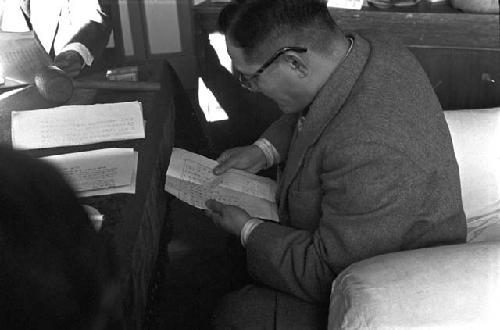 Man in suit privately reading paper during meeting