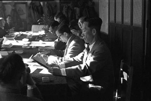 Portrait of men in suits at table going over papers