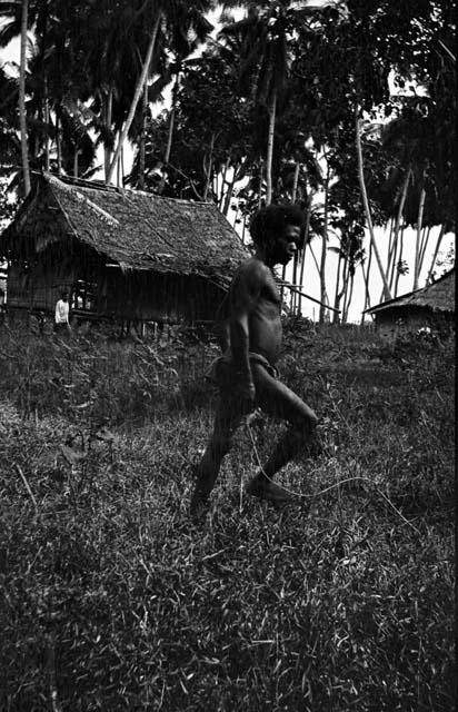 Man walking, structures and trees in background