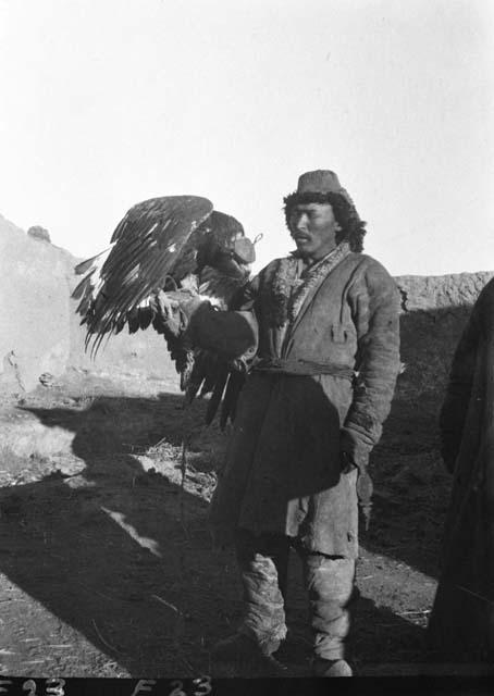 Qazaq, man standing with large hooded eagle on his arm