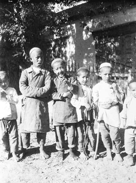 6 barefoot boys standing in front of building