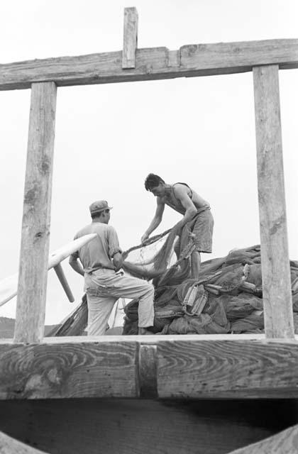 Two men hauling nets in front of wooden altar