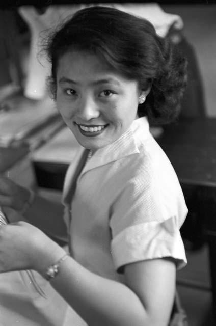 Woman sitting down wearing white dress smiling