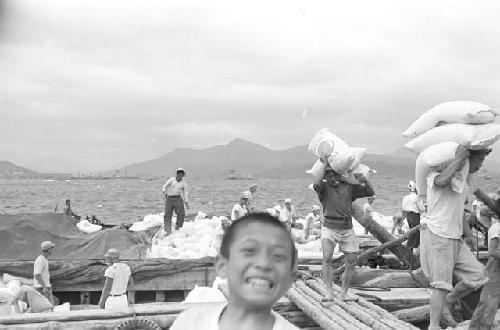 Portrait of men carrying rice bags by ship bay