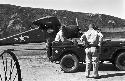 Soldiers waiting in jeep, plane in background