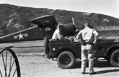 Soldiers waiting in jeep, plane in background