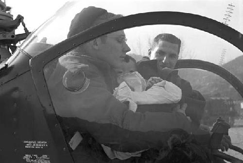 Soldier holding baby in chopper