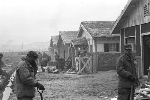 SoldieRS/Workers digging around houses on dirt road