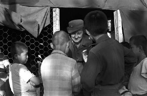 Kids gathered around soldier outside tent