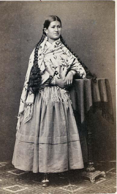 Woman, standing with elbow on table, long braids