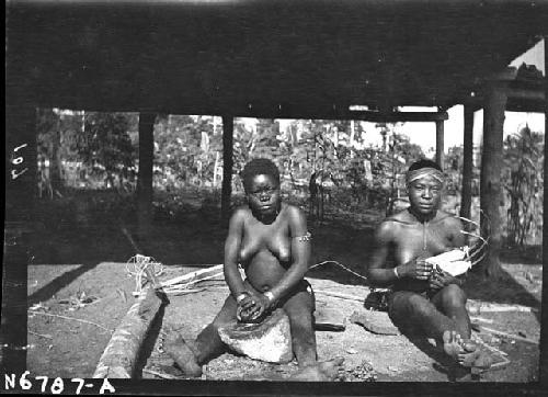 Two women grinding peanuts