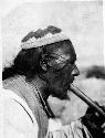 Side-view portrait of man wearing hat and playing flute