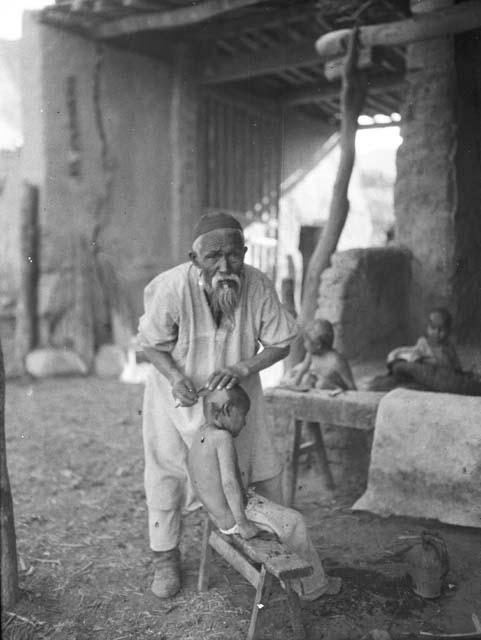 Old Turki shaving child's head