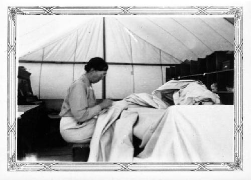 Hattie Cosgrove mending tent canvas torn in wind storms