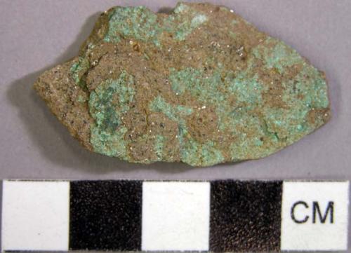 Stone fragment with green substance on surface.