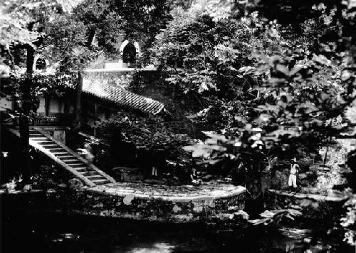 Elaborate terrace, steps and buildings in trees at side of lake or pool