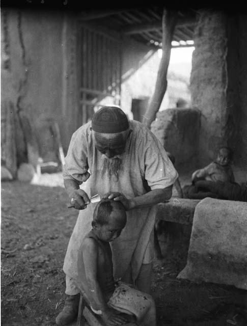 Old Turki shaving child's head