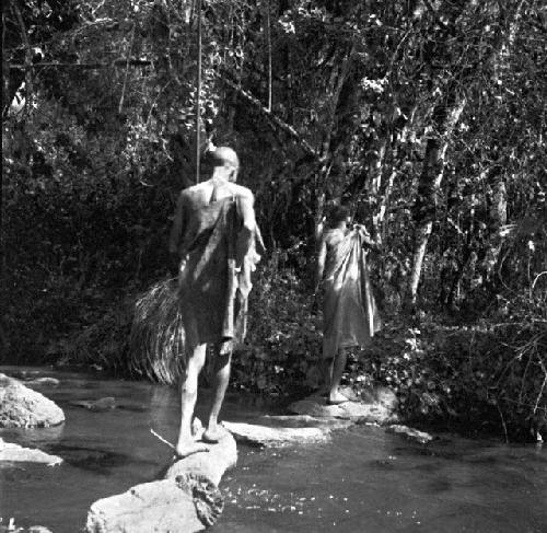 Masai crossing stream on stepping stones