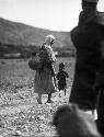 Woman and child on the road, woman with jar on back